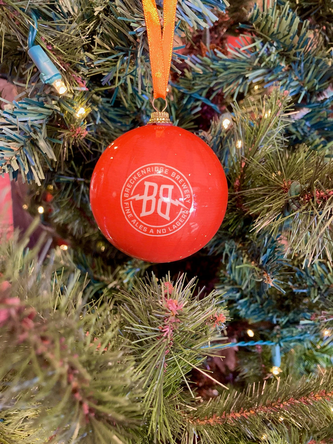 A red ornament ball hang on the tree featuring the Breckbrew Logo