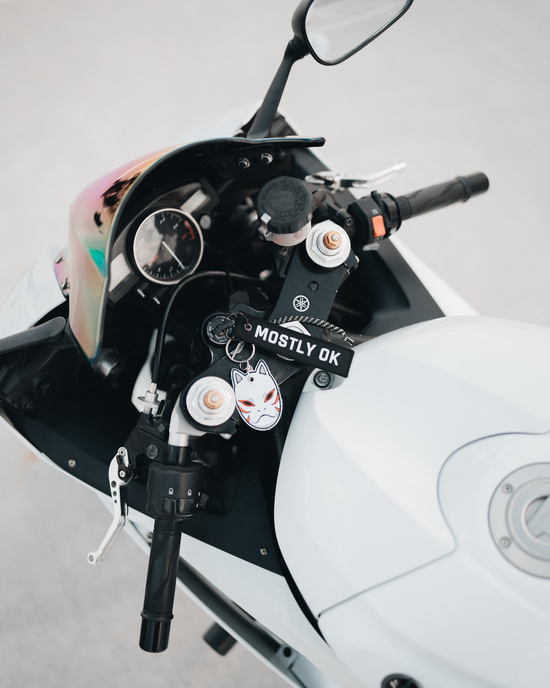 A motorcycle with a camera attached, all kinds of keychains, captured in a close-up shot.